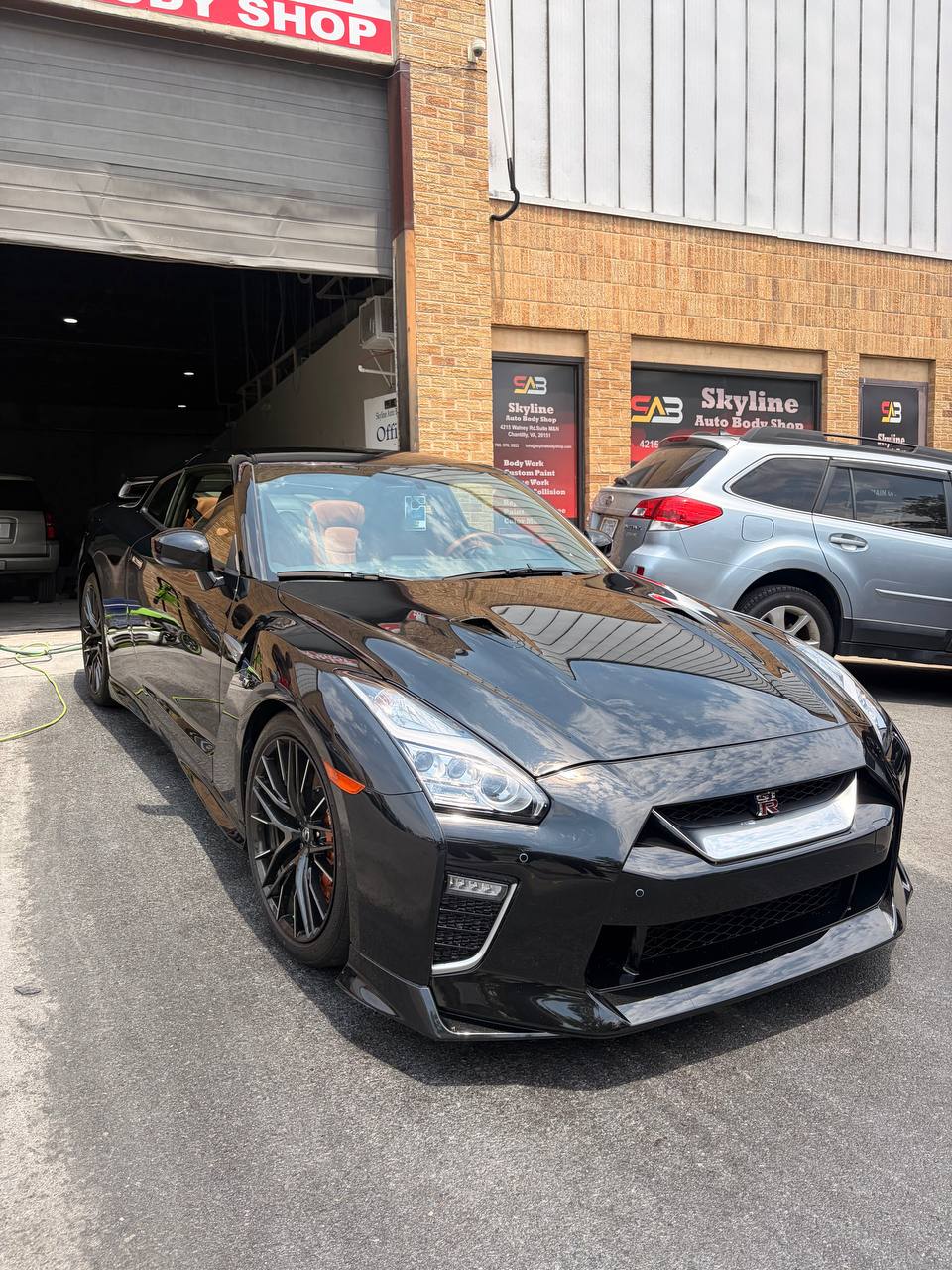 A 2021 Nissan GT-R with full front STEK DYNOshield paint protection film and Gtechniq ceramic coating, glossy under the bay lights at Skyline Custom Shop in Chantilly, VA.